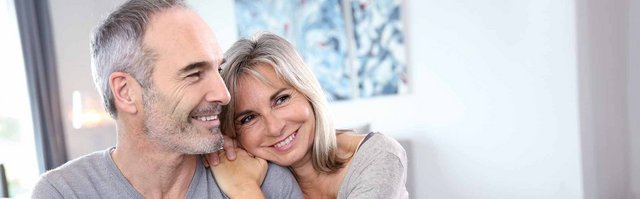 Ein lächelndes Paar genießt einen intimen Moment in einem hellen Raum, umgeben von moderner Kunst an der Wand.