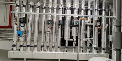 Eine Reihe von isolierten Rohren und Messgeräten in einem technischen Raum, die für die Überwachung von Flüssigkeiten verwendet werden.