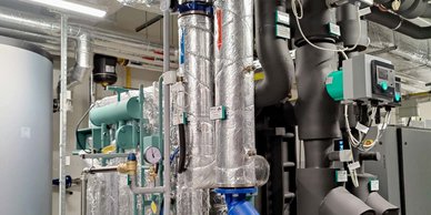 Eine komplexe Anordnung von Rohren und Maschinen in einem technischen Raum, die für industrielle Prozesse genutzt wird.